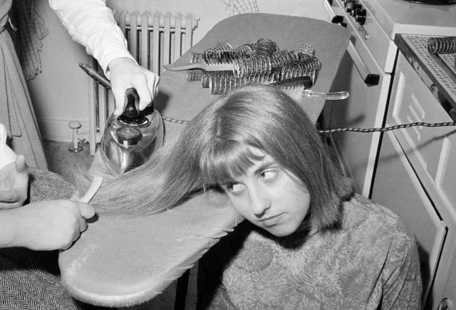 1964年，一位14岁女孩在和朋友外出前用熨斗拉直头发