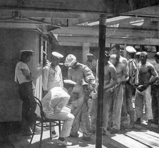 这张照片拍摄于1910年,展示了一名海军医生检查从岸上休假返回的水兵