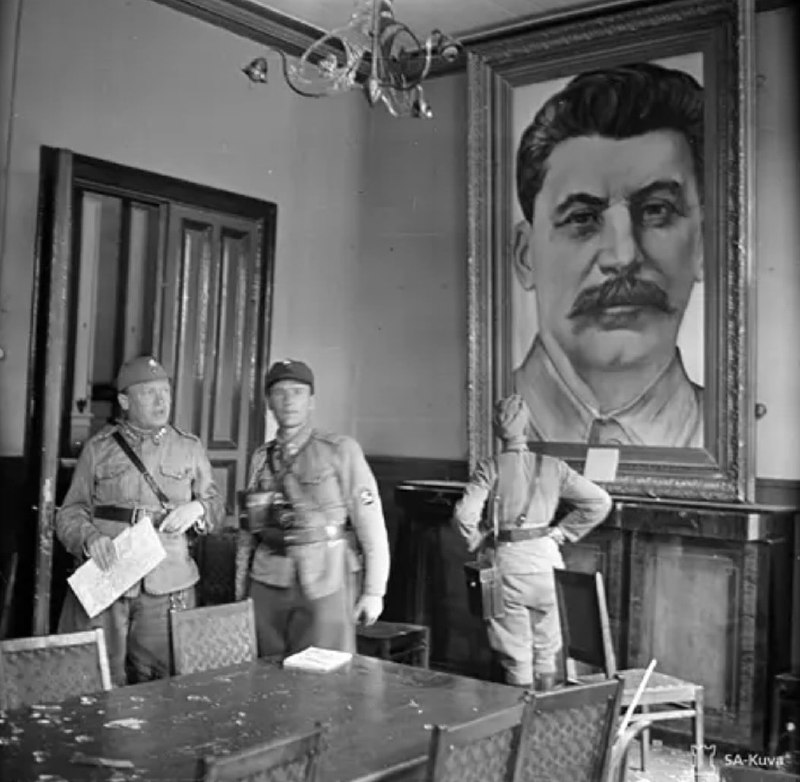 1941年，芬兰士兵站在索尔塔瓦拉市政厅的斯大林画像旁，在继续战争开始时，小镇被安特罗·斯文森(左)重新夺回