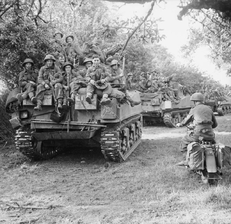 这张照片展示了1944年7月18日发起的古德伍德行动中，英国第三师的步兵们是如何通过坐在斯塔福德郡游骑兵团的谢尔曼坦克上前往战斗区域的