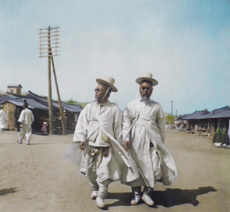 1904 年，两名戴墨镜的韩国男子一起走在韩国的街道上
